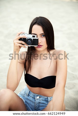 Girl taking photos with retro camera on beach