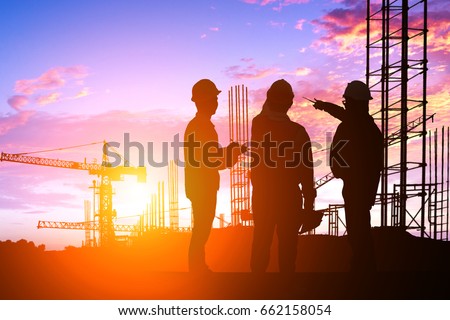 Silhouette Teams engineer looking construction worker in a building site at sunset Royalty-Free Stock Photo #662158054