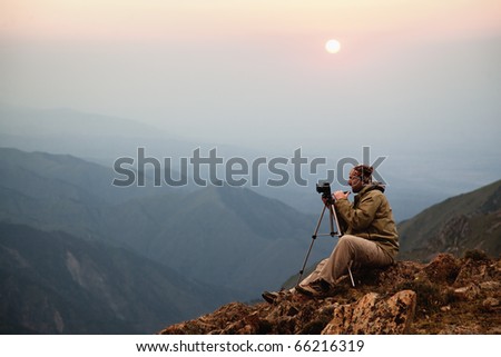 Photographer in the mountains at sunset