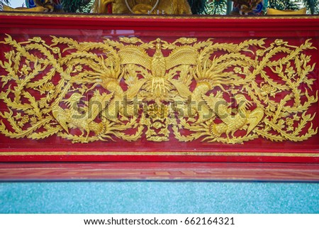 Beautiful golden Chinese phoenix birds engraved on the red wall in Chinese temples.
