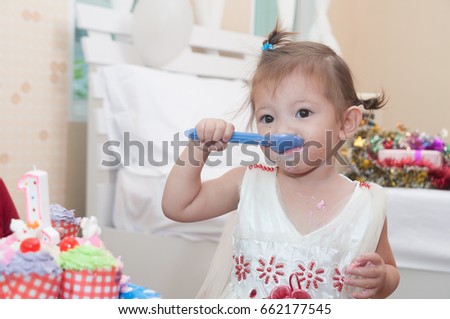 Child 1 year 2 months eating many birthday cup cake with her mom, there are a lot of present box on white bed,  family happy time.