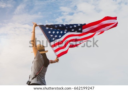 Young asian woman holding American flag on blue sky background