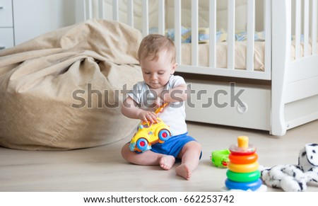 10 months old baby playing on floor with toy car and blocks Royalty-Free Stock Photo #662253742