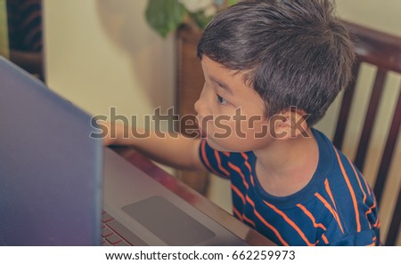 image of Asian cute boy using computer laptop on table at home.