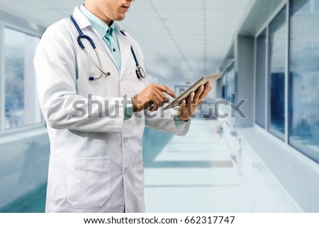 Male doctor working on computer tablet in the hospital or office background. Concept of medical data analysis for healthcare business.