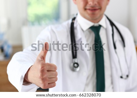 Smiling male medicine doctor showing OK sign with thumb up at office portrait. High level work, confident satisfied male do like, visit to clinic, best occupation, emergency help, teamwork concept
