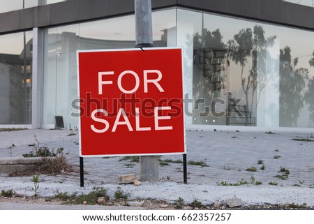 A abandoned home is advertising a for sale sign on a sign post in red