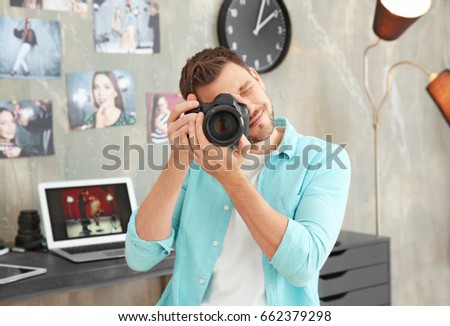 Young photographer with camera in office