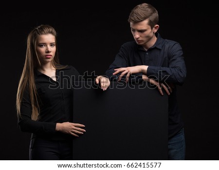 Young serious couple portrait of a confident businessman showing presentation, pointing paper placard background. Ideal for banners, registration forms, presentation, landings, presenting concept.