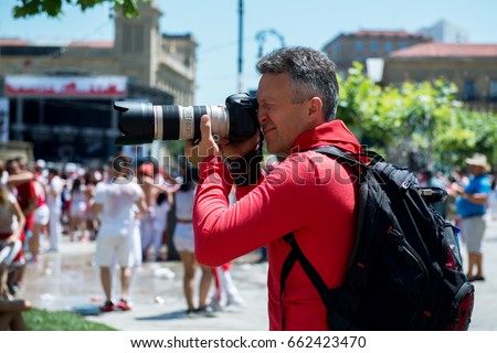 Photographer on San Fermin. Photojournalist. People celebrate San Fermin festival in traditional white and red clothing with red necktie, 06 July 2016, Pamplona, Navarra, Spain. Royalty-Free Stock Photo #662423470