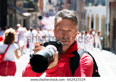 Photographer on San Fermin. Photojournalist. People celebrate San Fermin festival in traditional white and red clothing with red necktie, 06 July 2016, Pamplona, Navarra, Spain. Royalty-Free Stock Photo #662423524