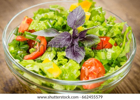 Plenty of cut vegetables on glass bowl on rustic wooden table, closeup
