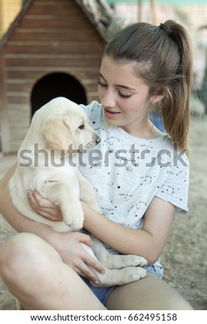 Portrait of a teenage girl with a golden retriever puppy.