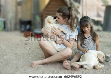 Portrait of two sisters with a golden retriever puppy.