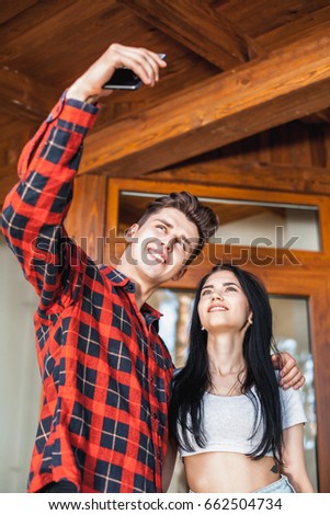 Happy romantic couple taking a photo with smart phone. Beautiful young girl and man hug and laugh taking a selfie. Urban fashion style