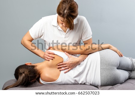 Close up of female osteopath doing shoulder blade therapy on young woman. Royalty-Free Stock Photo #662507023