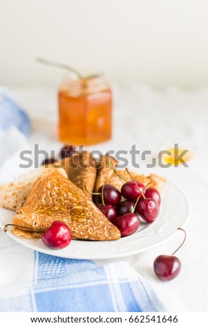 Whole gran pancakes with honey and cherries. Useful breakfast. Homemade thin pancakes. 