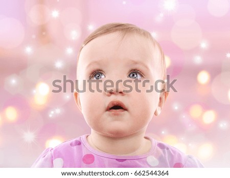 Cute baby girl on blurred lights background. Holidays celebration concept