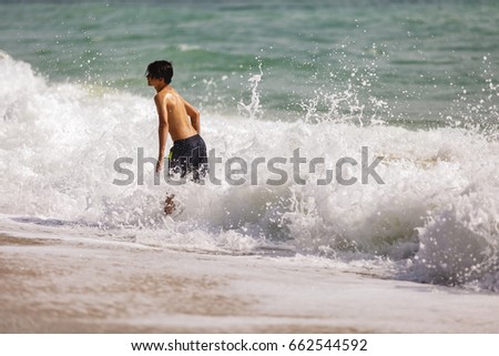 Beautiful young boy playing in the waves