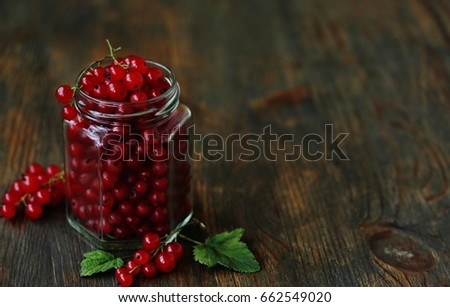 Red currant in a glass jar on an old wooden background. Canning of berries. Planned to make jam from red currant. Soft focus. Place for text.  Copy Space