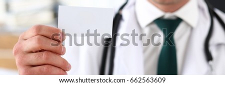 Male physician hand holding and giving white blank calling card closeup in office. Contact information exchange, introducing gesture at formal meeting, success, personal or family doctor concept