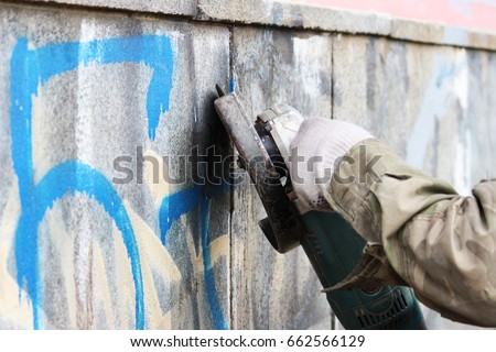 Removal of graffiti on a concrete wall of an underground passage with the help of a angle grinder. Royalty-Free Stock Photo #662566129