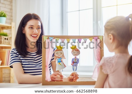 Happy loving family. Mother and her daughter in kids room. Funny mom and lovely child having fun and playing performance in the puppet theater indoors. Prince and princess. Royalty-Free Stock Photo #662568898