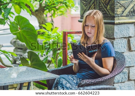 Beautiful woman ordering from menu in restaurant and deciding what to eat.