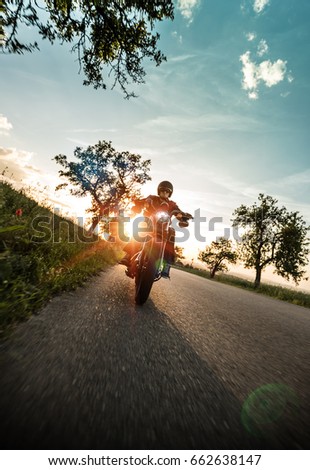 Man riding sportster motorcycle on countryside during sunset. Royalty-Free Stock Photo #662638147