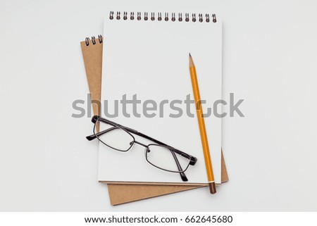 Two notebooks lying on a white table With glasses and pencil, office concept
