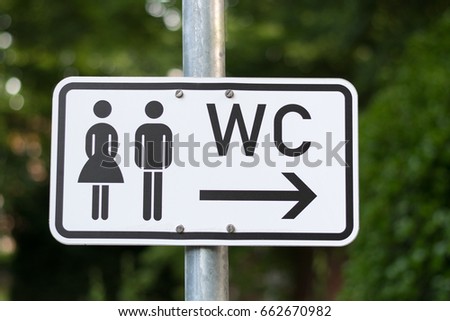 A WC sign isolated on a pole in a park