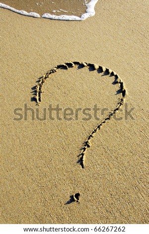 a question mark drawn on the sand of a beach