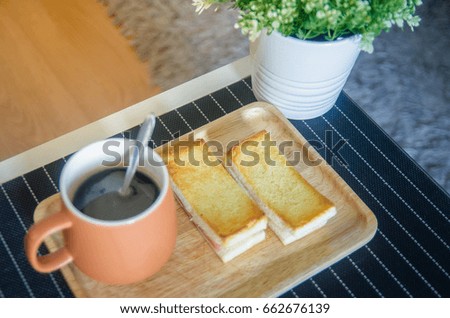 Breakfast on the Morning, black coffee in brown cup and Sliced bread with ham put on the black table.