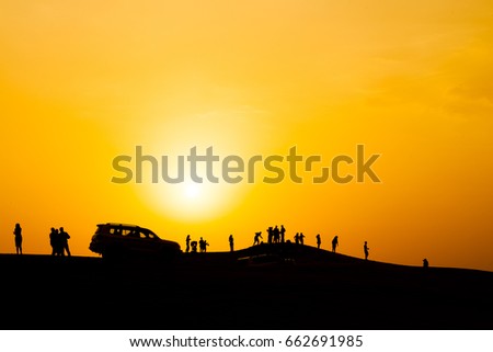 Silhouette of people in dubai desert, with sunset.