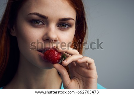 Woman eating strawberries, sweet strawberries, woman with strawberries on gray background portrait                               