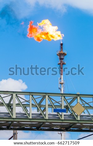 Fire of gas burning from flare structure in oil refinery plant with blue sky