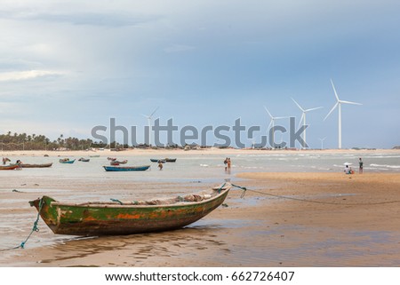 Boat and wind farm in the background at "Pedra do Sal" beach - Paui, Brazil Royalty-Free Stock Photo #662726407