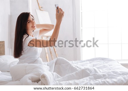 Young brunette taking selfie portrait with smartphone