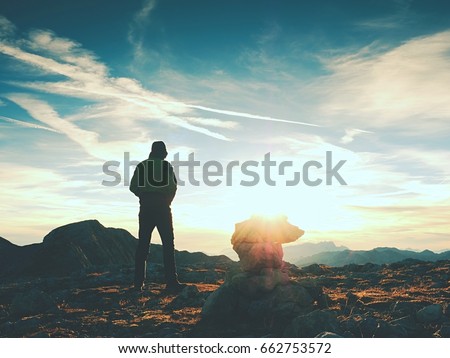 Tourist guide at stocked stones on Alps peak. Strong hiker enjoy sunset in   Alpine mountain. Alone man on few days trek