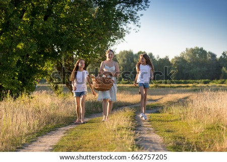 Happy girls walking with with mother on countryside road