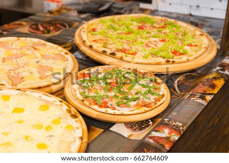 Tasty pizzas with variety of toppings and cheese on wooden trays at outdoor food festival