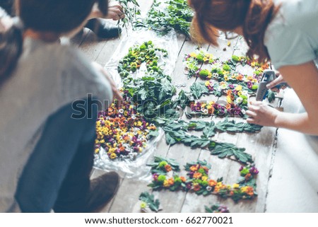 Florists making flower decoration with letters and glue. Indoors natural light shot with small depth of field