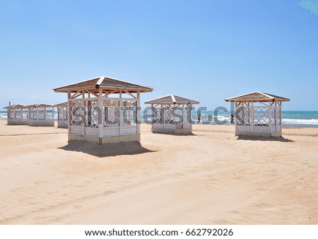 white wooden pavilions on sandy sea beach
