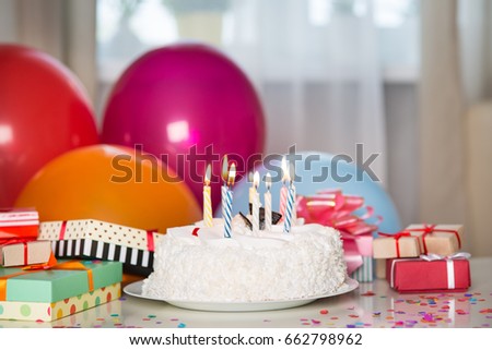 Birthday cake with candles on the table with gifts