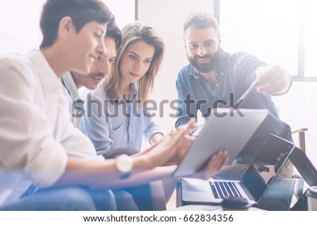 Concept of presentation new business project.Group of young coworkers discussing ideas with each other in modern office.Business people using electronic devices.Horizontal, blurred background Royalty-Free Stock Photo #662834356