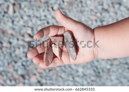 Summer. Sunny day. On the palm of the child are beautiful stones. A picture on the background of rubble