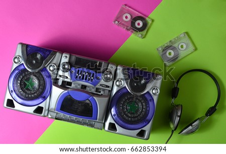 A tape recorder with cassettes and headphones on a red green neon background. Top view.