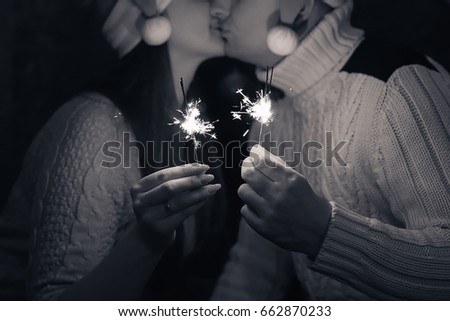 People Holding Sparklers. Couple kissing in warm clothes