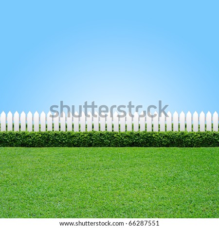White fence and green grass on blue sky
