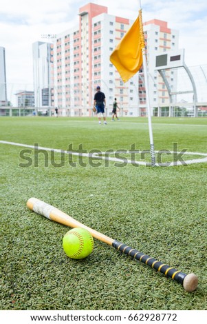 bat wood and softball on grass field and blurry player